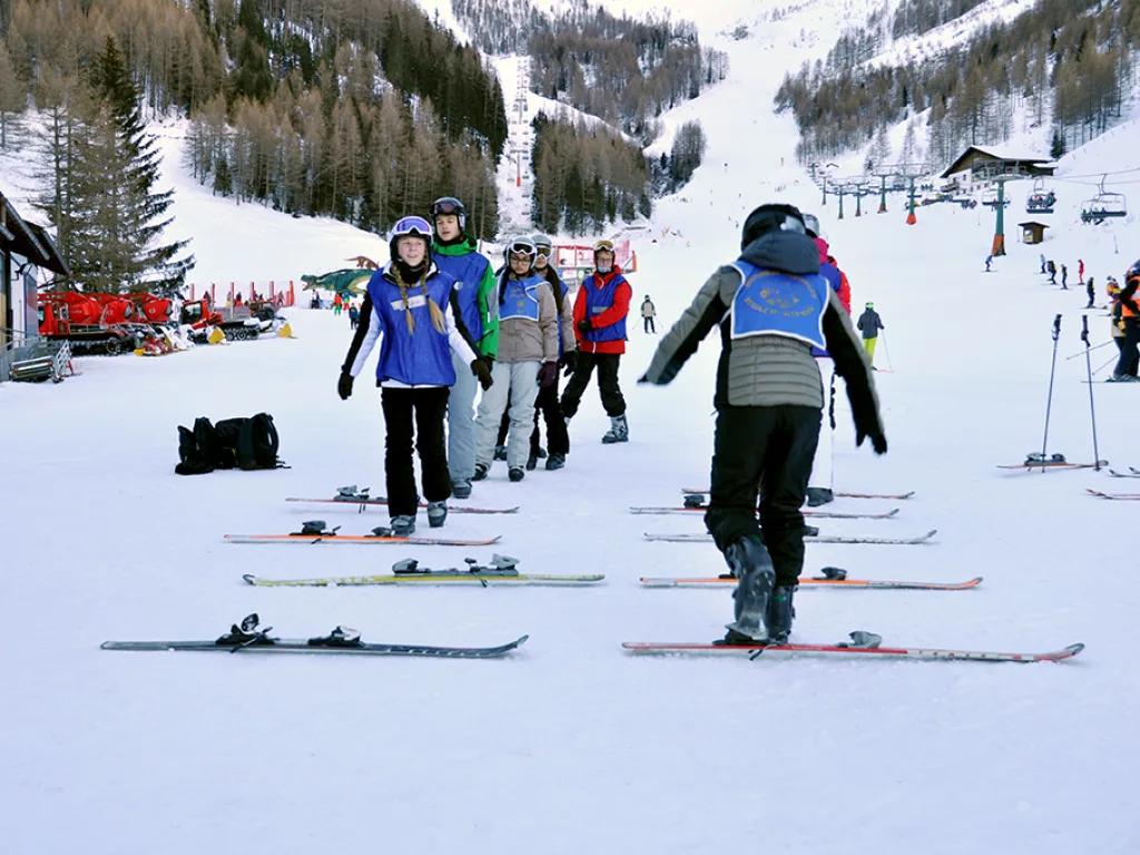 Jugendliche gehen mit ihrer Ausrüstung über die Piste.